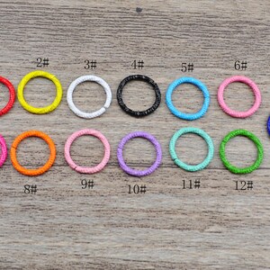 May include: Thirteen colorful metal hoops, numbered 1 through 13, arranged in two rows on a wooden surface. The hoops are various colors, including red, yellow, white, black, blue, pink, orange, green, and purple.