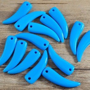 May include: A collection of 14 blue plastic beads shaped like a tooth or fang. Each bead has a hole drilled through the top for stringing.