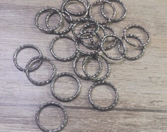 May include: A collection of silver-toned metal rings, some with a textured finish, arranged on a wooden surface.