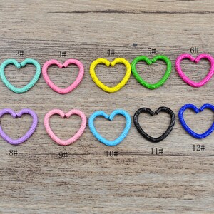 Può includere: Tredici anelli di metallo a forma di cuore in vari colori, tra cui rosso, blu, verde, rosa, arancione, viola, giallo e bianco. Gli anelli sono numerati da 1 a 13.