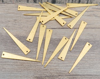 May include: A collection of gold-colored metal triangle shapes with a hole at the top. The triangles are scattered on a wooden surface.