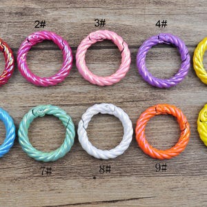Puede incluir: Nueve anillos de metal retorcidos de colores brillantes con cierre a presión. Los anillos están numerados del 1 al 9.