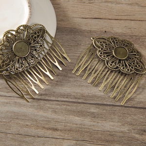 May include: Two antique bronze-colored hair combs. Each comb features a floral filigree design with a central circular setting. The combs have multiple tines for securing in hair. The combs are displayed on a wooden surface.