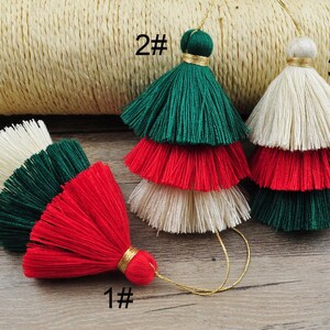 Puede incluir: Tres borlas de tres capas en verde, rojo y blanco. Las borlas son hechas a mano y tienen un borde con flecos. Las borlas están etiquetadas con 1#, 2# y 3#.