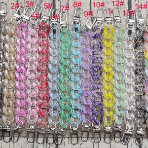 Puede incluir: Quince cadenas de plástico transparente con cierres plateados. Las cadenas son de varios colores, incluyendo negro, rosa, rojo, azul, verde, morado y amarillo.