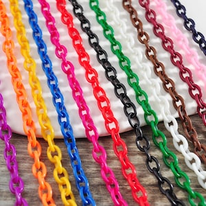 Könnte beinhalten: Sortiment an bunten Plastikketten in verschiedenen Farben, darunter lila, orange, gelb, blau, rot, rosa, braun, weiß, schwarz und grün.