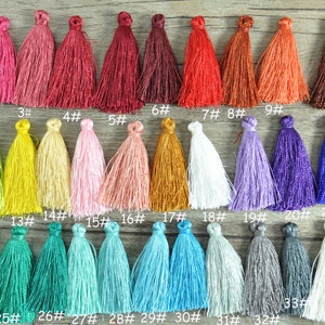 May include: Thirty-five colourful tassels in various shades of red, pink, orange, yellow, green, blue, purple, brown, and white. The tassels are arranged in rows and numbered 1 through 35.