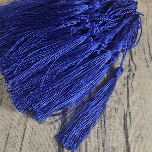 May include: A bundle of royal blue tassels, crafted from soft, silky threads, are tied together. The tassels are all the same size and have a long, flowing fringe.