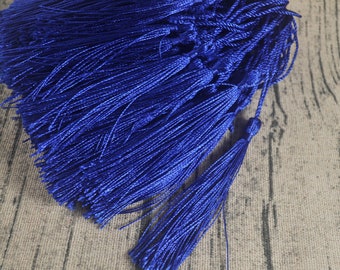 May include: A bunch of royal blue tassels, made of soft, silky threads, are bundled together. The tassels are all the same size and have a long, flowing fringe.
