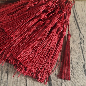 May include: A bundle of deep red tassels with a knotted top. The tassels are made of a soft, silky material and are perfect for adding a touch of elegance to any project.