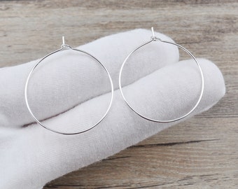 May include: A pair of silver hoop earrings. The earrings are simple and elegant, and they would be a great addition to any jewellery collection.