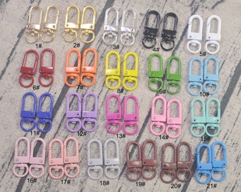 Puede incluir: Veintiún pares de llaveros de metal en varios colores, incluyendo dorado, plateado, negro, blanco, rojo, naranja, amarillo, verde, azul, morado, rosa y marrón. Cada llavero tiene un gancho giratorio y un anillo en D.