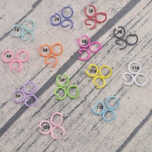 May include: Assortment of 13 jump rings in various colors, including pink, blue, green, yellow, red, black, and white. Each ring is labeled with a number from 1 to 13.