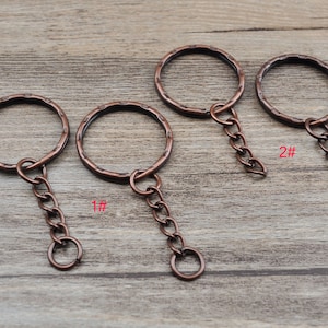 May include: Three copper key rings with attached chains. The key rings are different sizes. The largest key ring is labelled "2#" and the smallest key ring is labelled "1#"
