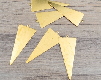 May include: Six gold-toned triangle-shaped metal charms with a hole at the top for hanging. The charms are on a light brown wooden surface.