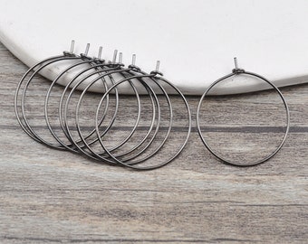 May include: A set of eight black hoop earrings. The hoops are made of metal and have a simple, circular design.