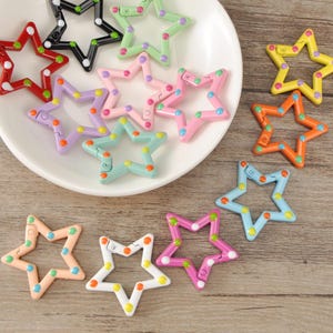 May include: A selection of star-shaped clasps in a variety of colours, including red, black, green, pink, purple, orange, yellow, and blue. Each clasp features colourful polka dots and a hinged design for easy attachment.