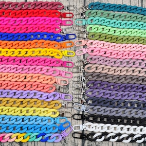 Puede incluir: Una colección de 33 correas de cadena de plástico de colores con cierres plateados y negros. Las cadenas están dispuestas en filas, con cada fila numerada del 1 al 33. Las cadenas son todas del mismo tamaño y estilo, pero son de diferentes colores.