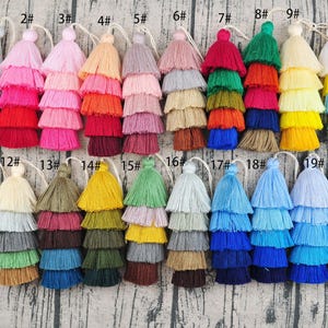 May include: Twenty multi-coloured tassel trims with three layers of fringe. The tassels are numbered 1 through 20.