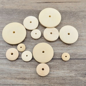 May include: Assortment of ten round wooden sanding discs of varying sizes. The discs are beige in colour and have a hole in the centre.