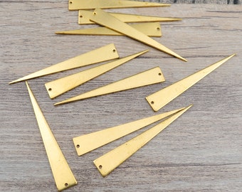 May include: A group of 12 gold-colored metal triangle shapes with a hole at the top. The triangles are arranged in a random pattern on a wooden surface.