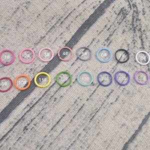May include: Assortment of 16 colorful metal jump rings in various sizes, labeled with numbers 1 through 16. The rings are arranged in two rows of eight.