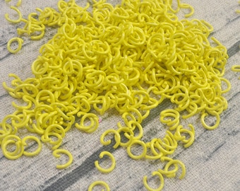 Könnte beinhalten: Ein großer Haufen leuchtend gelber Metall-Sprünge. Die Ringe sind alle gleich groß und in einem zufälligen Muster angeordnet.