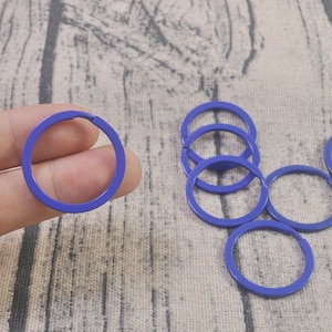 May include: A set of six blue metal key rings. The key rings are all the same size and shape, and they are arranged in a circle.