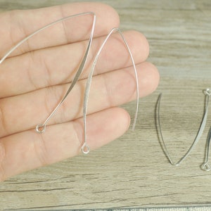 Puede incluir: Tres alambres de plata para pendientes con bucles en los extremos. Los alambres están doblados en forma de curva.