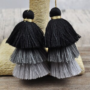 May include: Two-tiered black and gray tassel earrings with a gold accent at the top.