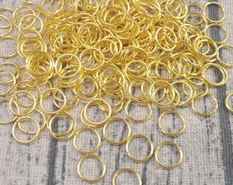 Puede incluir: Un montón grande de anillos de salto dorados, un tipo de anillo de metal utilizado en la fabricación de joyas.