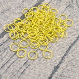 May include: A large pile of bright yellow metal jump rings. The rings are all the same size and are arranged in a random pattern.