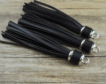 May include: Three black leather tassels with silver metal rings. The tassels are made of thin strips of leather and are about 6 inches long.