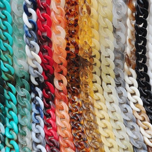 Puede incluir: Una colección de eslabones de cadena de plástico de colores en varios colores, incluyendo turquesa, blanco, rojo, naranja, marrón, beige y negro.