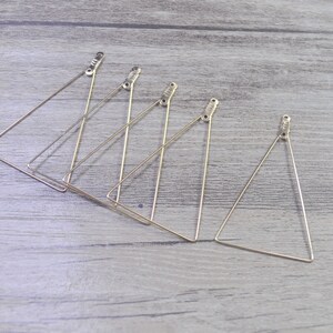 May include: Five gold triangle-shaped wire hoops, each with a small loop at the top.