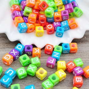 Può includere: Perle colorate con lettere dell'alfabeto in vari colori, tra cui rosso, arancione, giallo, verde, blu, viola e rosa. Le perle sono in plastica e hanno una forma quadrata. Ogni perla ha una lettera dell'alfabeto stampata su di essa.