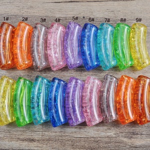 May include: Nine glass beads in various colors, including orange, pink, blue, green, and yellow. The beads are all shaped like a curved rectangle and have a textured surface.