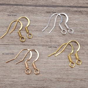 May include: A selection of earring hooks in different metallic finishes: raw brass, silver, gold, and KC gold. Each pair has a curved hook and a coiled spring detail, suitable for jewellery making.