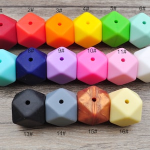 May include: A set of 16 silicone teething beads in various colors, including red, orange, yellow, green, blue, purple, pink, black, gray, and brown. The beads are shaped like hexagons with a hole in the center. The beads are numbered 1 through 16.
