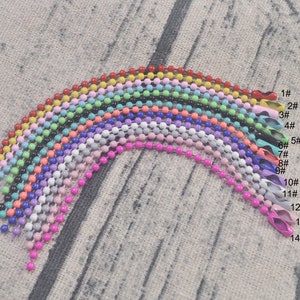 May include: Assortment of 14 colorful metal chains, each with a different color and size. The chains are arranged in a rainbow pattern, with the smallest chain at the top and the largest chain at the bottom.