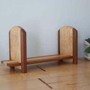 May include: A white ceramic mug with a black handle and the text "But First, Coffee" in a handwritten style. The mug is on a white surface. The mug is approximately 4 inches tall.