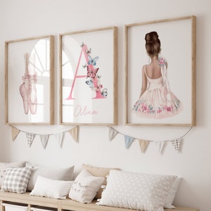 Chambre d'enfant décorée avec trois cadres accrochés au mur représentant des pointes de ballet, une lettre 'A' ornée de papillons et une danseuse de dos en robe fleurie