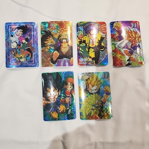 May include: Six holographic Dragon Ball Z trading cards featuring different characters from the anime series. The cards are in various colours, including blue, green, yellow, and red. The cards have a holographic finish and feature the Dragon Ball Z logo.