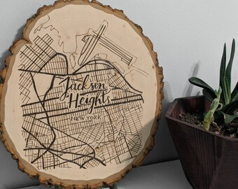 Puede incluir: Una rodaja de madera con un mapa de Jackson Heights, Nueva York, quemado. La madera es de color marrón claro y el mapa es de color marrón oscuro.