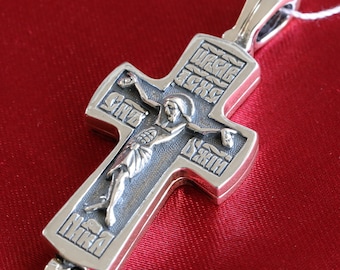 May include: A silver cross pendant with a detailed image of Jesus Christ on the cross. The cross is engraved with Cyrillic text.