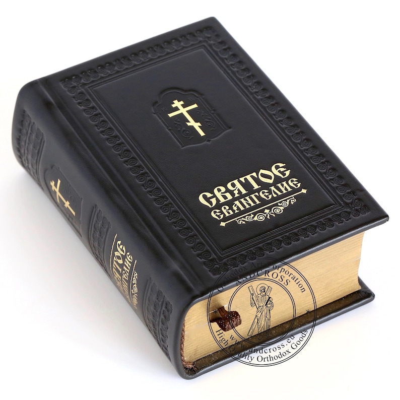 Pu&ograve; includere: Un libro rilegato in pelle nera con lettere dorate che recitano "Святое Евангелие" (Vangelo Santo). Il libro ha una croce dorata sulla copertina anteriore e un segnalibro dorato.