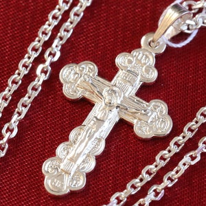 May include: A silver chain necklace with a detailed silver cross pendant. The cross features a figure of Jesus Christ and intricate floral designs.