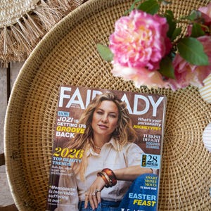 Puede incluir: Naturaleza muerta con una bandeja tejida, una revista, flores y tres tazas a rayas. La revista muestra a una mujer y el título "FAIR LADY". Rosas rosas y tazas a rayas añaden color a la escena.