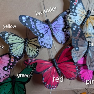 Peut inclure: Une collection de papillons d&eacute;coratifs artificiels dans diverses couleurs, notamment rose clair, jaune, lavande, taupe, marron, vert, rouge et rose. Chaque papillon pr&eacute;sente de fines antennes en fil de fer et des motifs d'ailes d&eacute;taill&eacute;s.