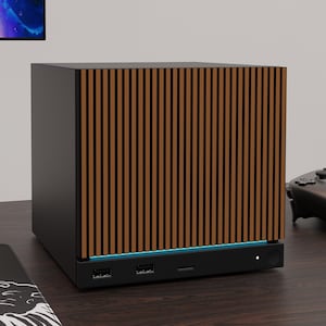 May include: A compact, cube-shaped computer case featuring a front panel with vertical brown wood-toned slats. The base of the unit is matte black with two USB ports, a USB-C port, a power button, and a thin strip of blue LED lighting underneath.